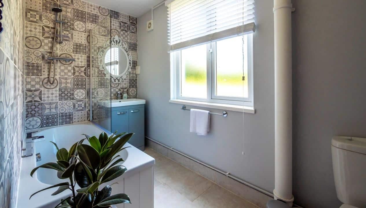 Monnow Valley Studio, Monmouthshire – Modern bathroom with patterned tile shower enclosure and teal vanity unit.