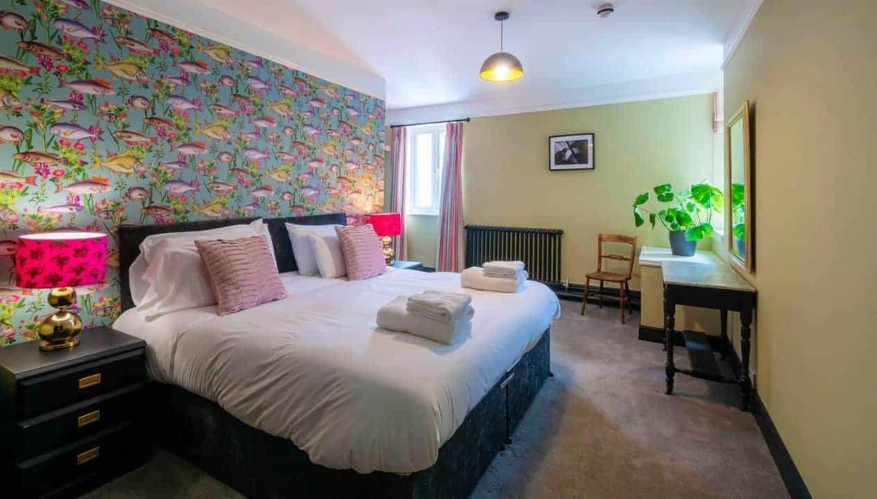 Monnow Valley Studio, Monmouthshire – Bedroom with floral wallpaper, double bed, and cream walls with radiator.