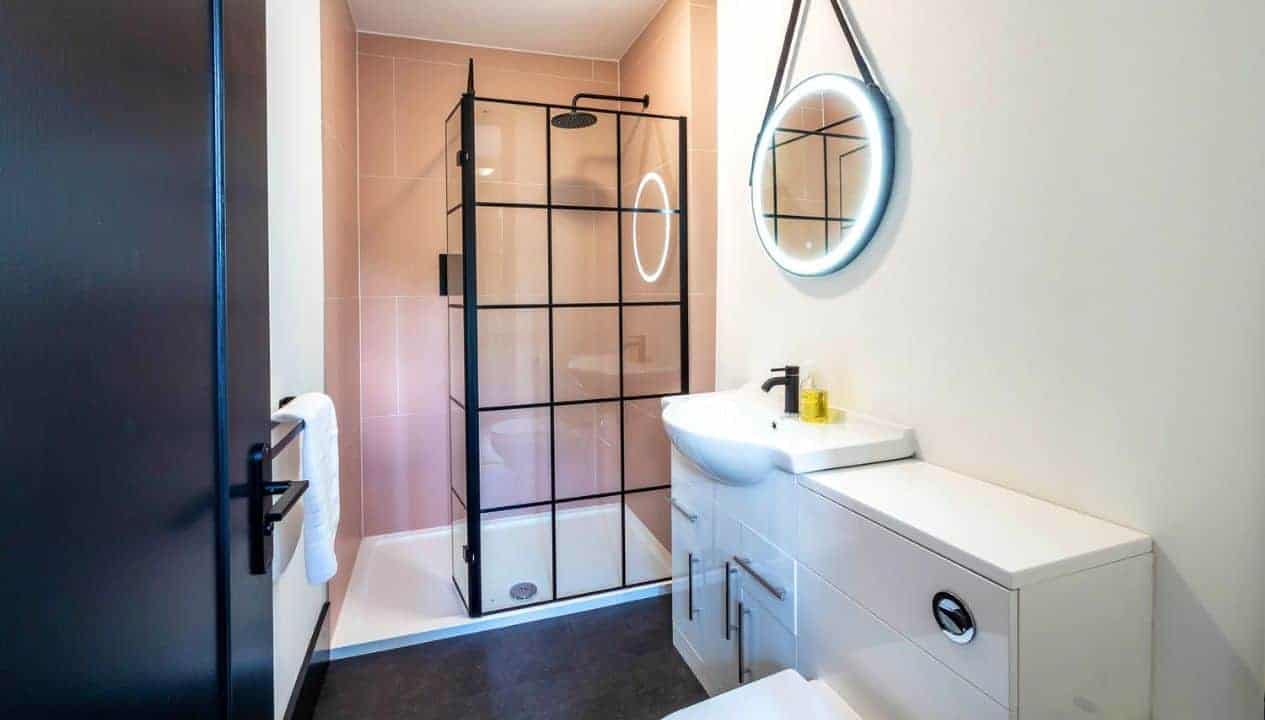 Monnow Valley Studio, Monmouthshire – Modern bathroom with black-framed shower enclosure and white vanity unit.