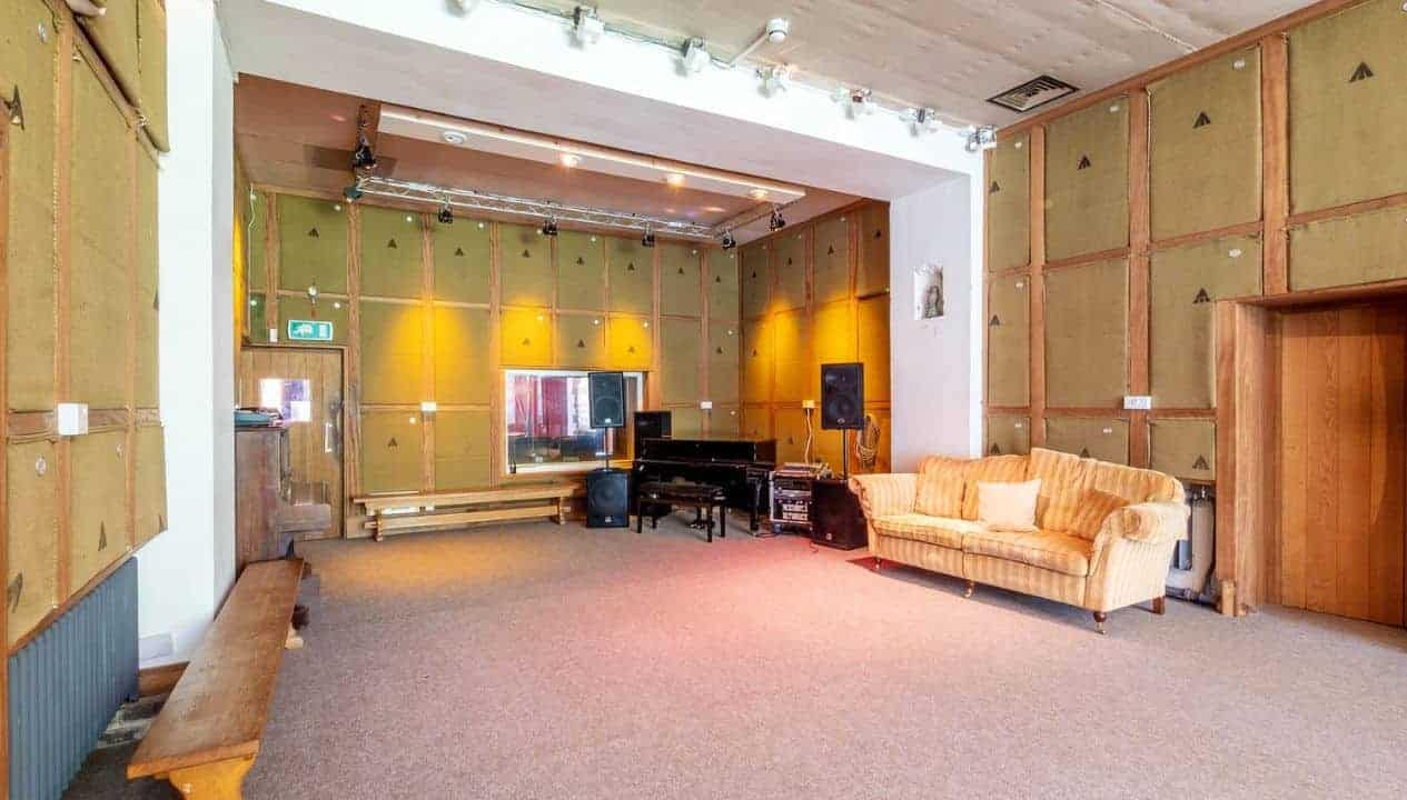 Monnow Valley Studio, Monmouthshire – Large music studio with grand piano, striped sofa, and timber-panelled walls.