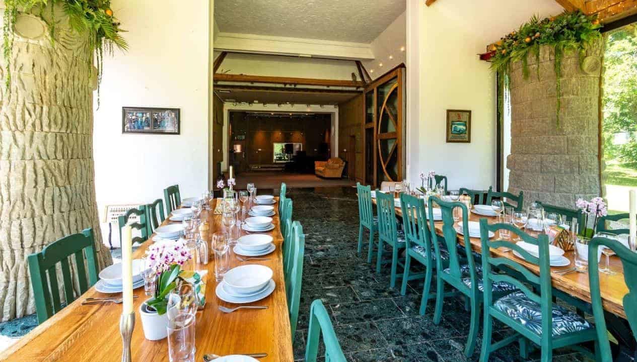 Monnow Valley Studio, Monmouthshire – Long dining table with green chairs and place settings, stone pillars, open-plan interior.