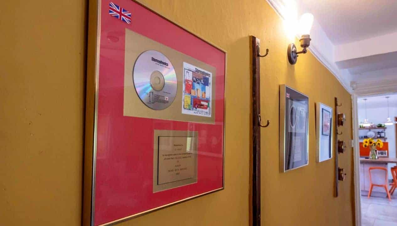 Monnow Valley Studio, Monmouthshire – Hallway with yellow walls displaying framed gold disc and certificate in red mount.