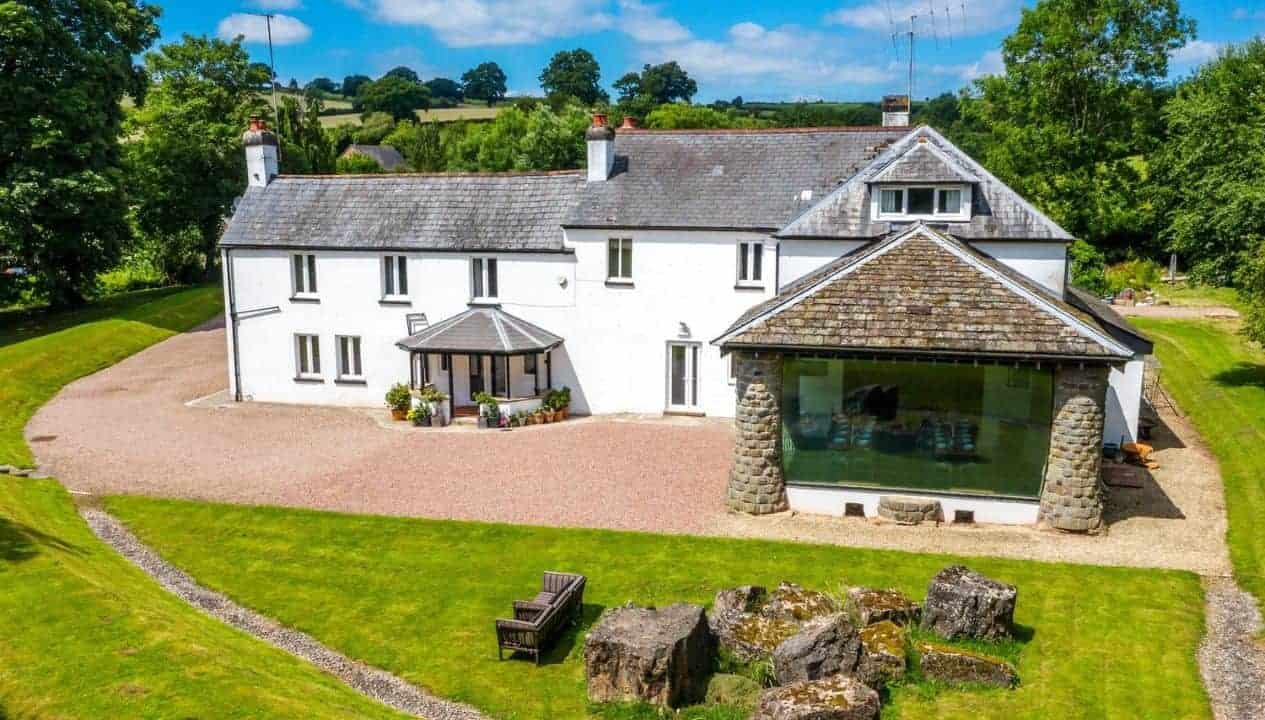 Monnow Valley Studio, Monmouthshire – Modern stone extension with large glazed gable adjoining whitewashed farmhouse, set in green countryside grounds.
