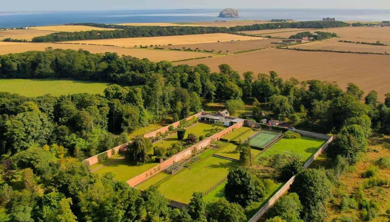 Leuchie Walled Garden – Aerial view of walled garden with brick walls, manicured lawns, and surrounding woodland overlooking countryside.