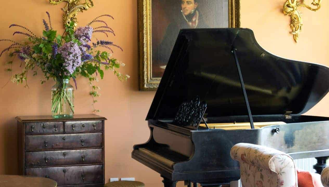 Leuchie Walled Garden – Grand piano, antique chest of drawers, and floral arrangement in elegant drawing room.