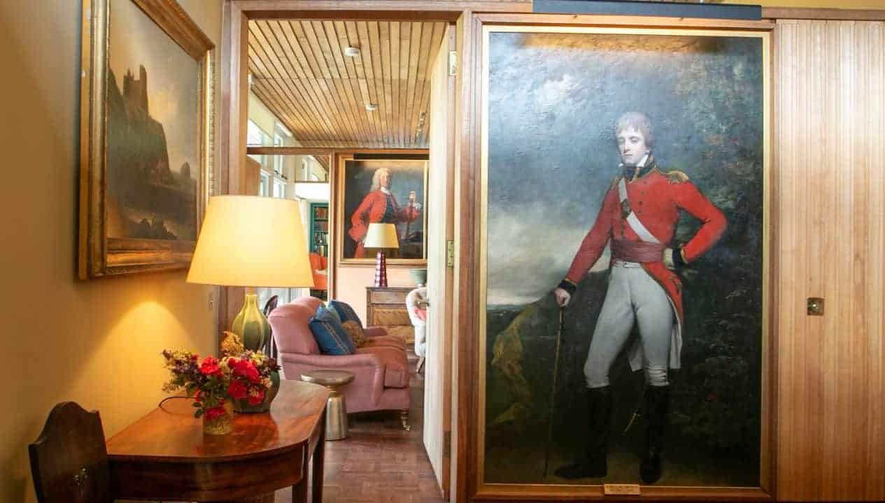 Leuchie Walled Garden – Hallway with period portrait painting, wood panelling, and table lamp with fresh flowers.