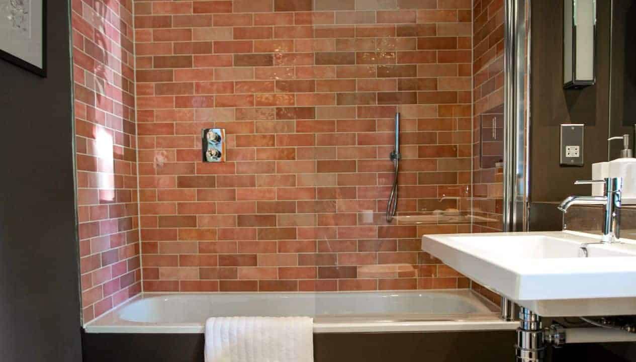 Leuchie Walled Garden – Modern bathroom with terracotta brick shower surround and white basin.