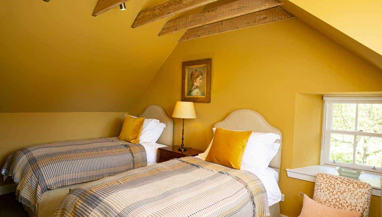 Leuchie Walled Garden – Attic bedroom with twin beds, exposed wooden beams, and mustard-yellow walls.