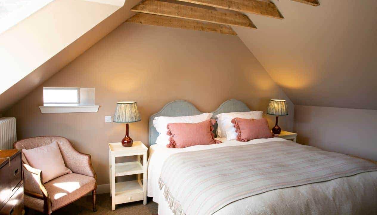 Leuchie Walled Garden – Attic bedroom with exposed wooden beams, double bed, and armchair.