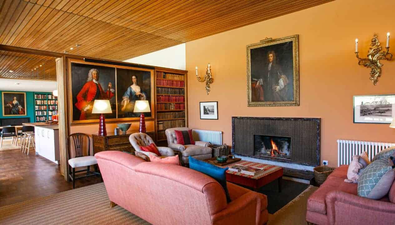 Leuchie Walled Garden – Spacious living room with pink sofa, fireplace, and portrait paintings on apricot walls.