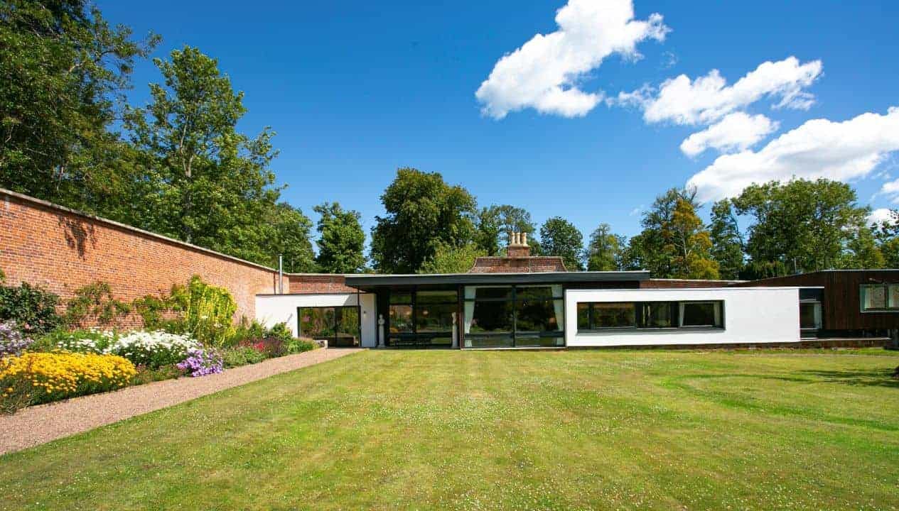 Leuchie Walled Garden – Modern single-storey extension with large windows overlooking manicured lawn and brick boundary wall.