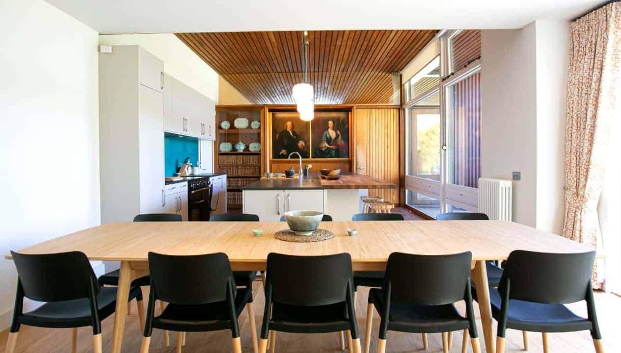 Leuchie Walled Garden – Open-plan kitchen and dining room with wooden ceiling and portrait artwork.
