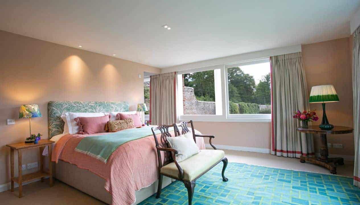 Leuchie Walled Garden – Spacious bedroom with pink bedding, large windows overlooking grounds, and turquoise geometric rug.