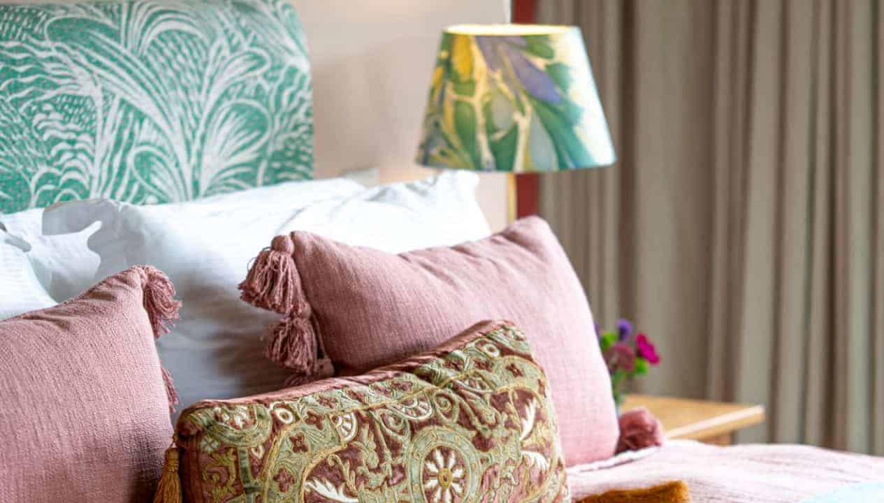 Leuchie Walled Garden – Bedroom with pink tasselled cushions, patterned lampshade and green headboard.