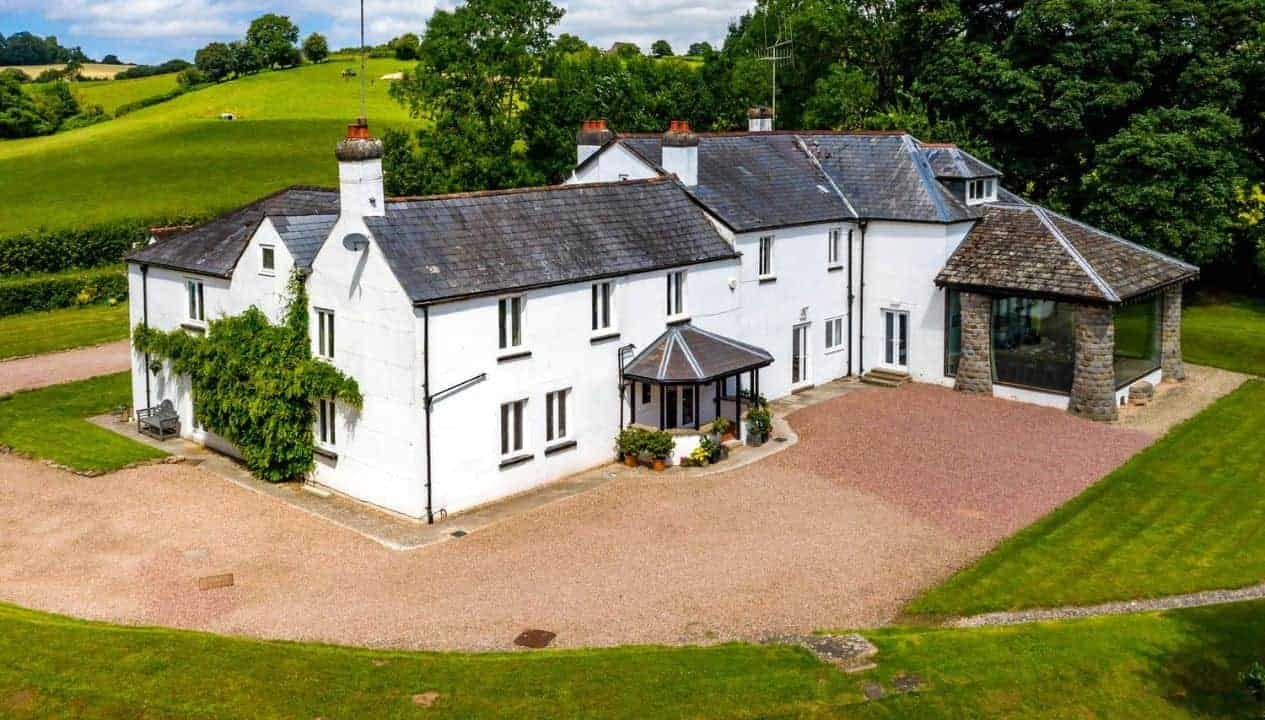 Monnow Valley Studio, Monmouthshire – White rendered country house with slate roof and gravel driveway surrounded by rolling green fields.