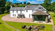 Monnow Valley Studio, Monmouthshire – Modern stone extension with large glazed gable adjoining whitewashed farmhouse, set in green countryside grounds.