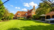 Catton Old Hall, Norfolk – Red-brick country house with terracotta roof and expansive lawn, timber-framed pavilion to right.