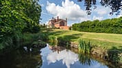 Barton Court, Herefordshire – Red brick country house with pond and manicured lawn bordered by hedges.
