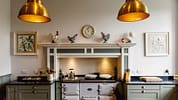 Boxted Hall, Suffolk – Kitchen with cream Aga cooker, brass pendant lights and tiled splashback.
