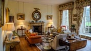 Gilmerton House, East Lothian – Formal drawing room with marble fireplace, gilded mirrors, and patterned curtains.