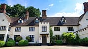 Hill House Norfolk, Norfolk – White-rendered country house with black casement windows and multiple brick chimneys.