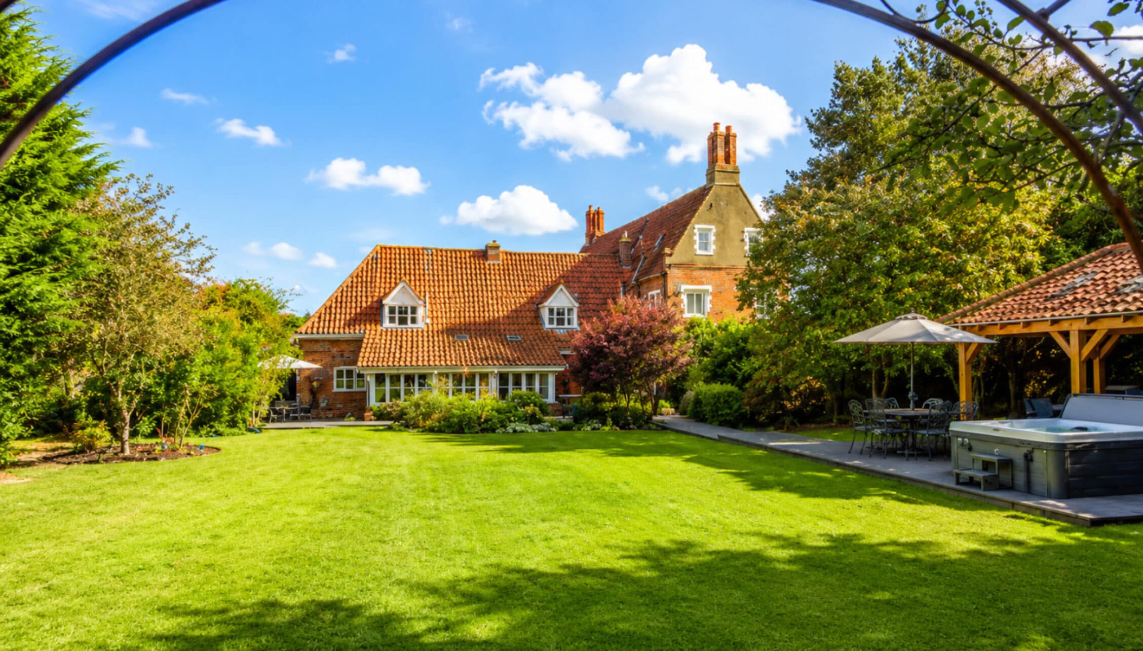 Catton Old Hall, Norfolk – Red-brick country house with terracotta roof and expansive lawn, timber-framed pavilion to right.