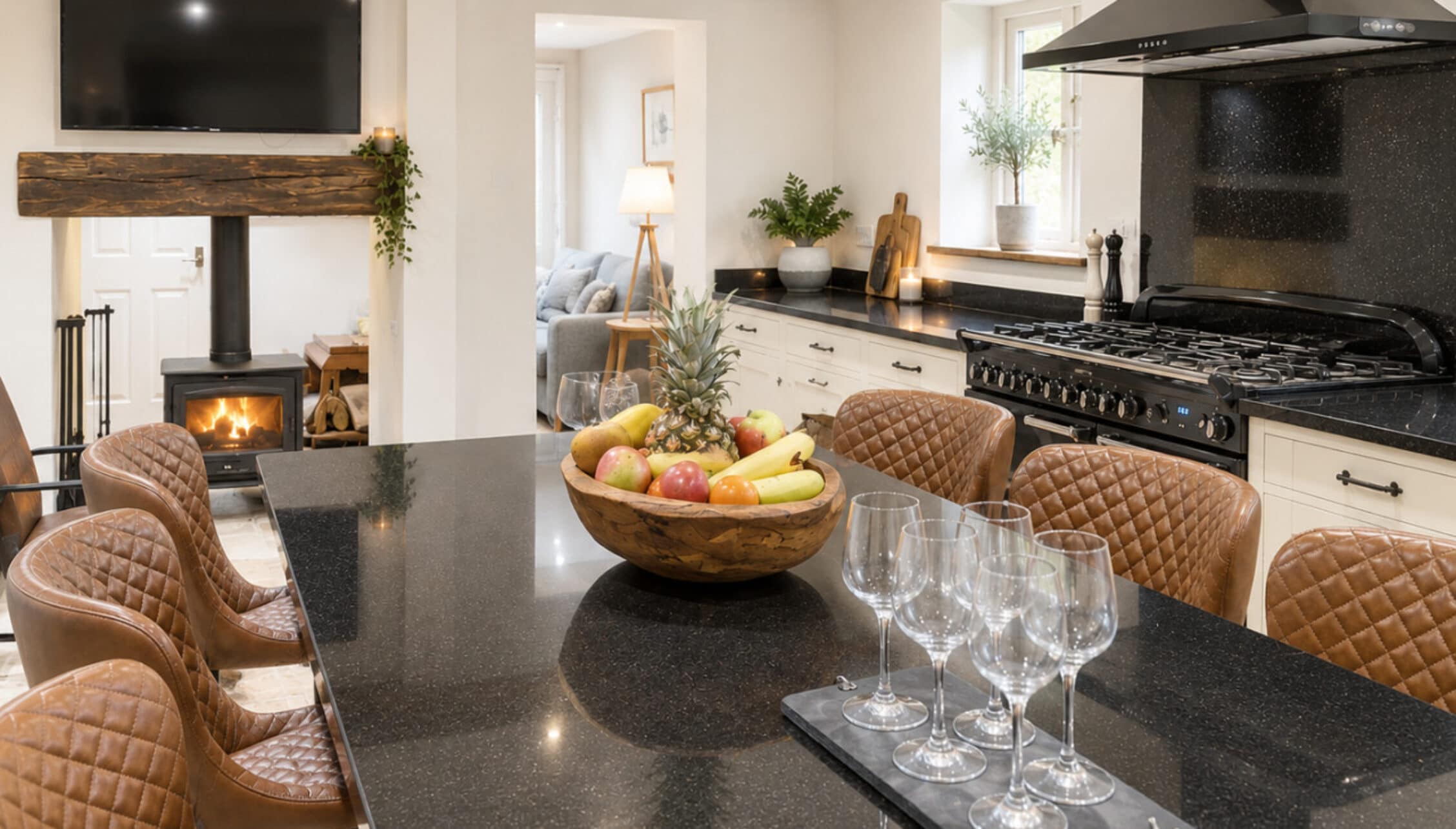 Catton Old Hall, Norfolk – Open-plan kitchen and dining area with dark stone countertops, Aga cooker, and tan leather chairs.