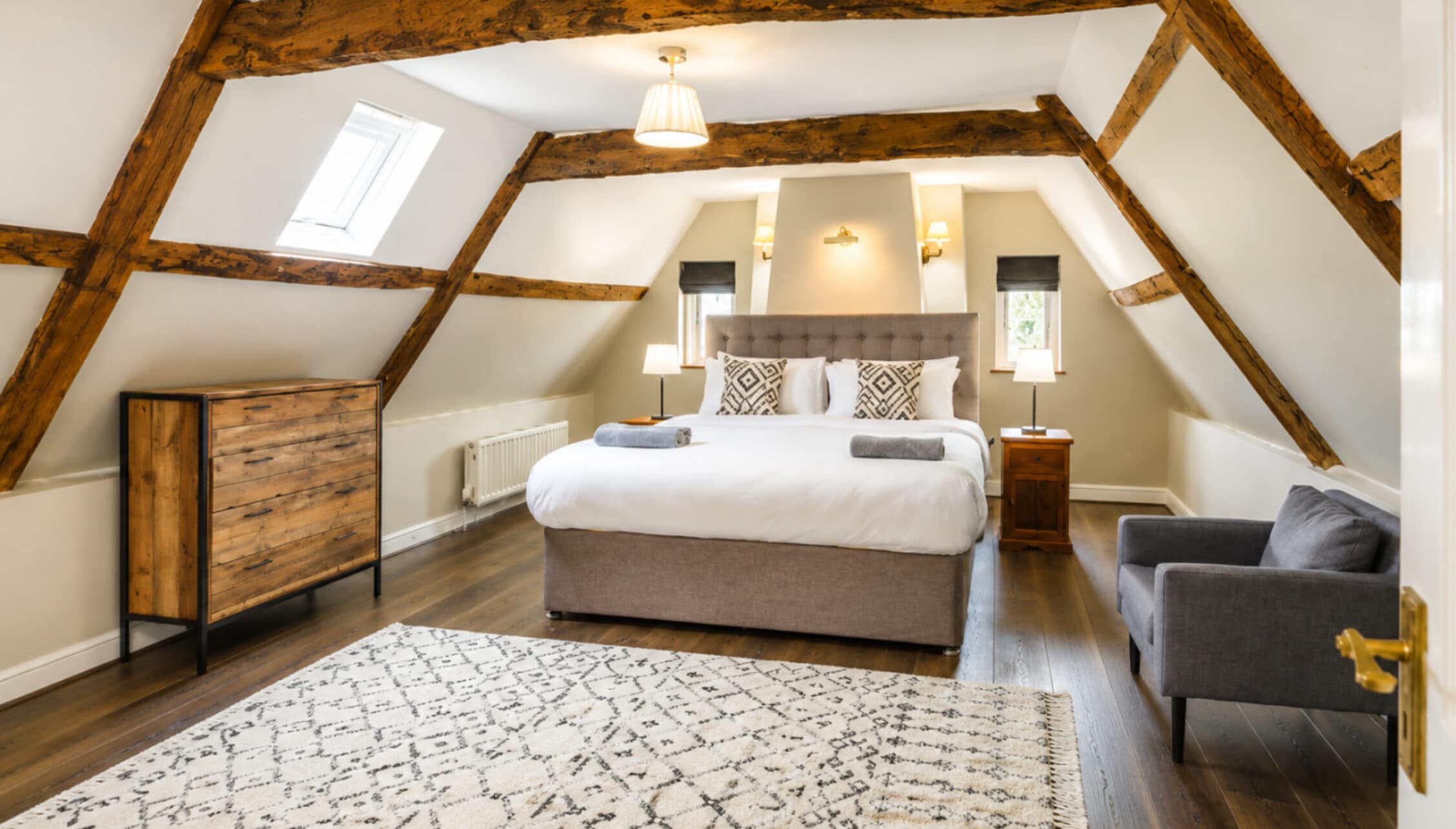 Catton Old Hall, Norfolk – Attic bedroom with exposed wooden beams, king bed, and skylights.