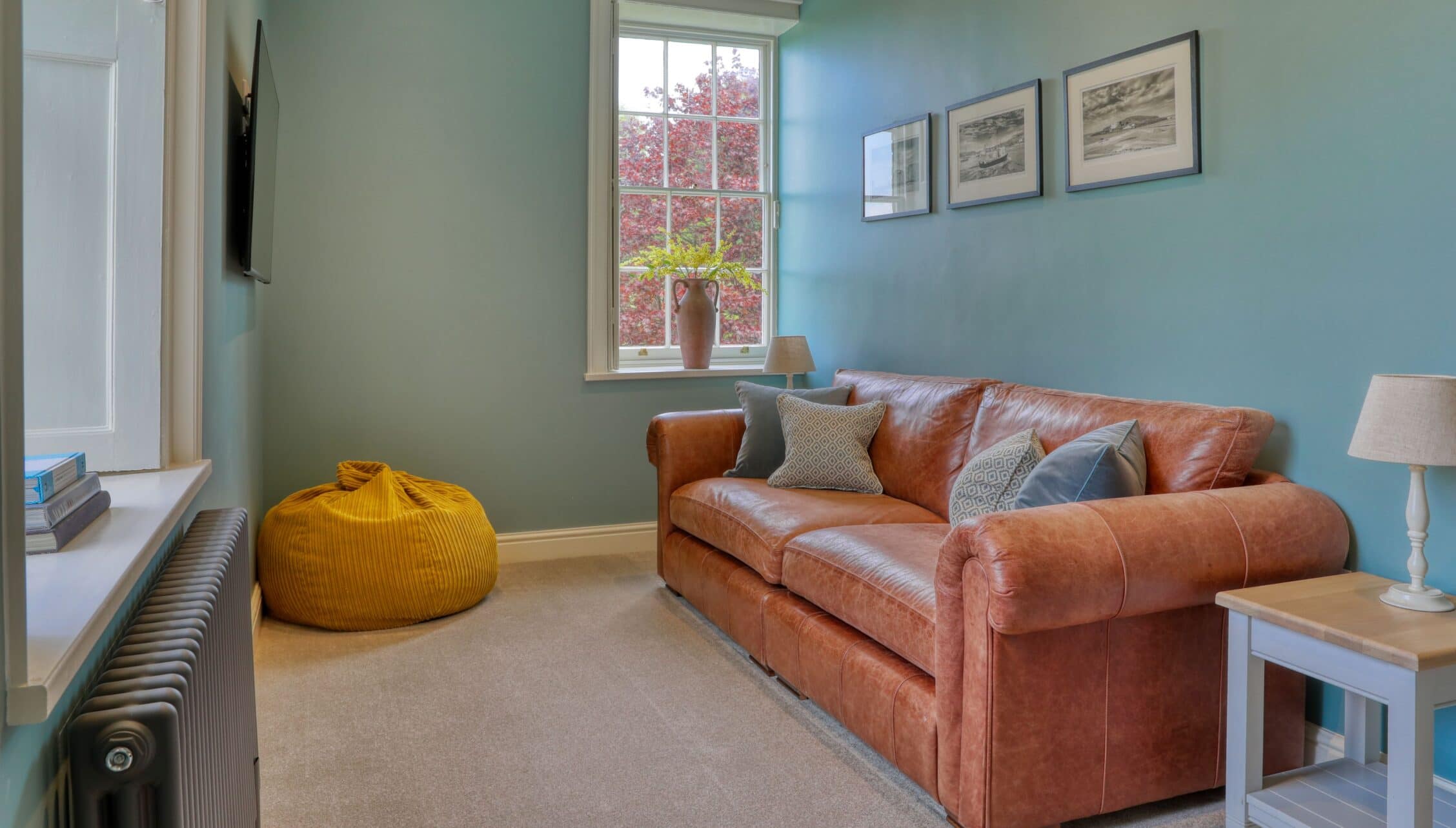 Gitcombe House, Devon – Sitting room with cognac leather sofa, sash window, and sage-green walls.