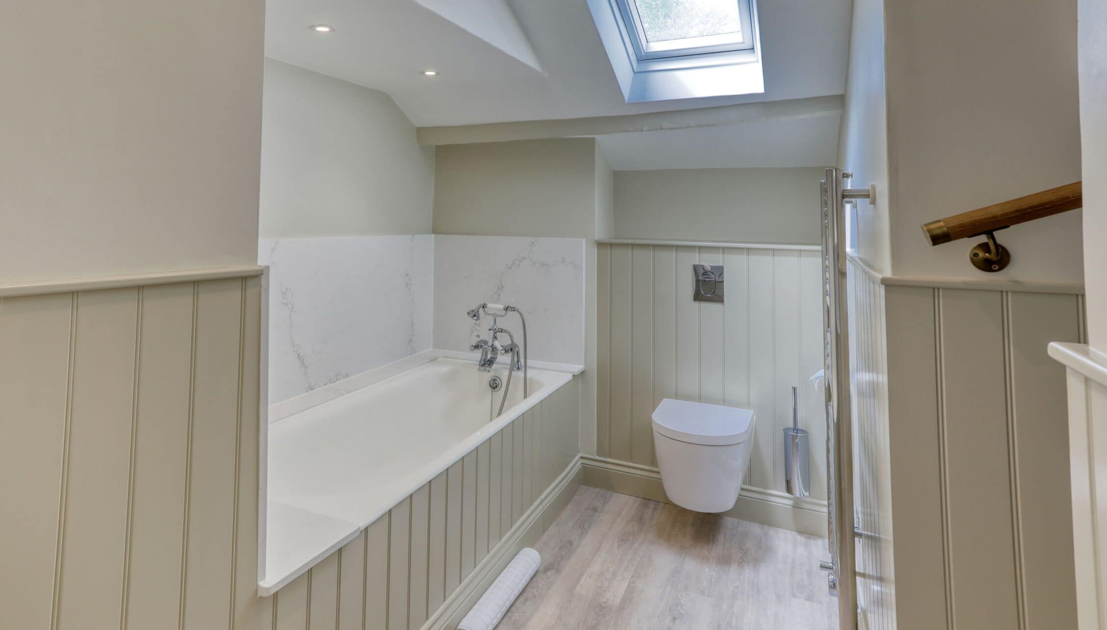 Gitcombe House, Devon – Modern bathroom with freestanding bath, wall-mounted toilet, and skylight.