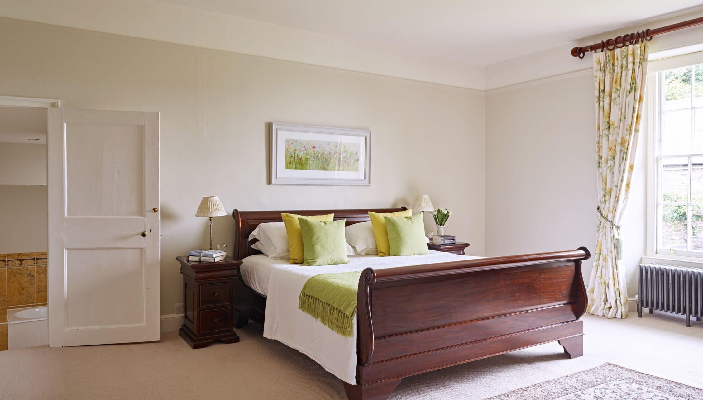 Gitcombe House, Devon – Bedroom with mahogany sleigh bed, cream walls, and patterned curtains.