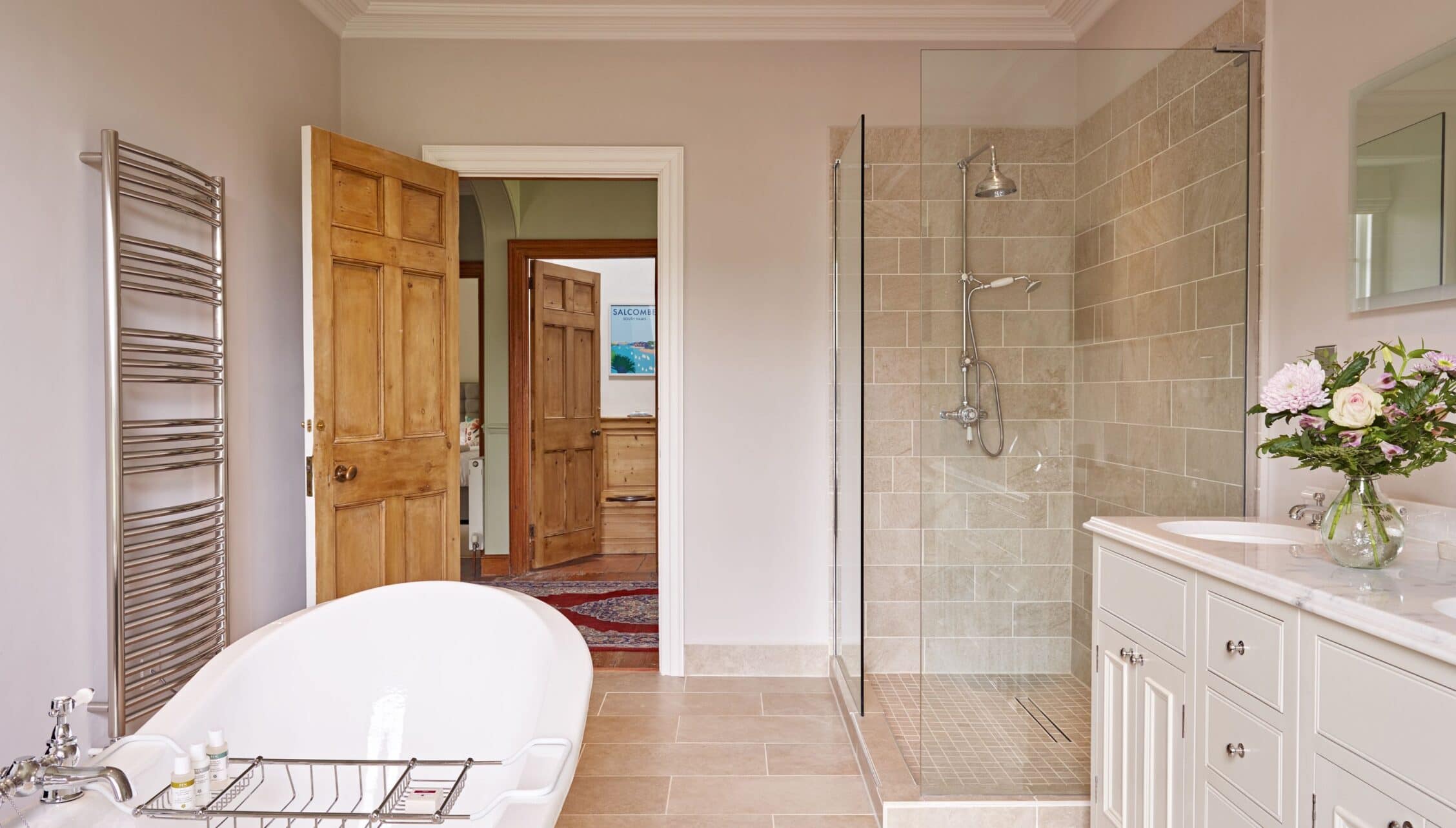 Gitcombe House, Devon – Spacious bathroom with freestanding bath, walk-in shower enclosure and wooden doors.