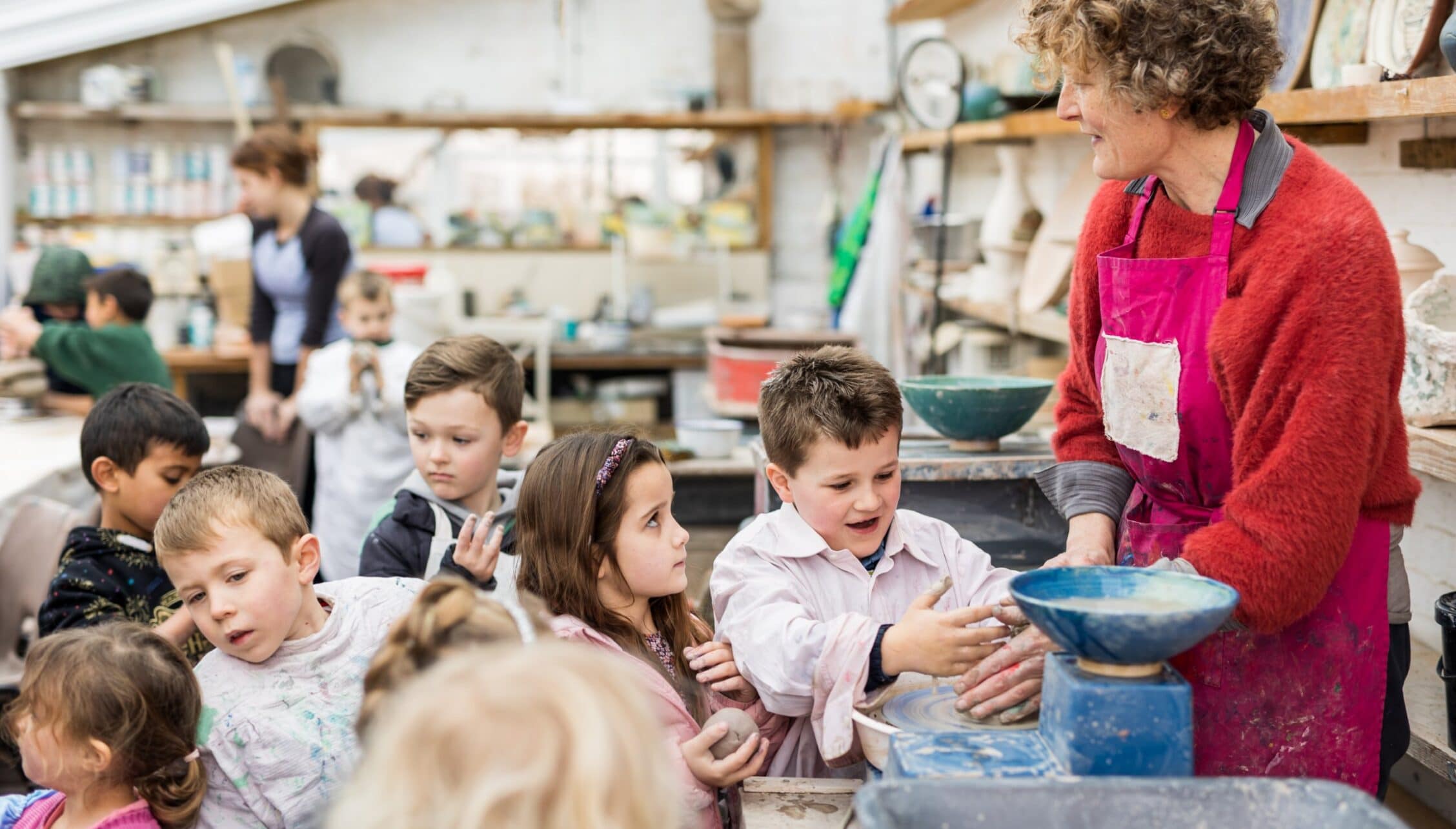 Upper Court, Gloucestershire – Children participating in pottery class with instructor in ceramic studio.