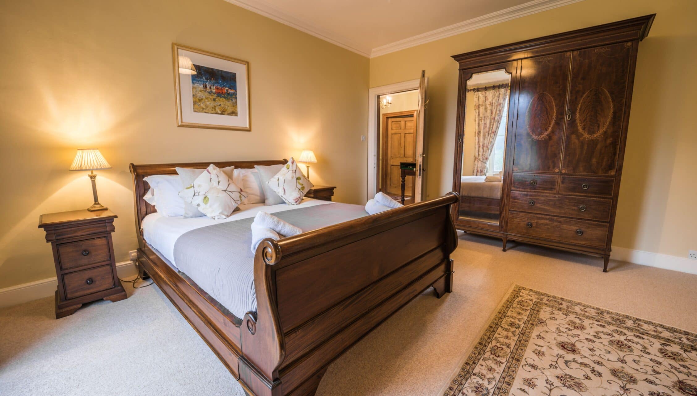 Gitcombe House, Devon – Spacious master bedroom with wooden sleigh bed, dark wood wardrobe, and cream carpet.