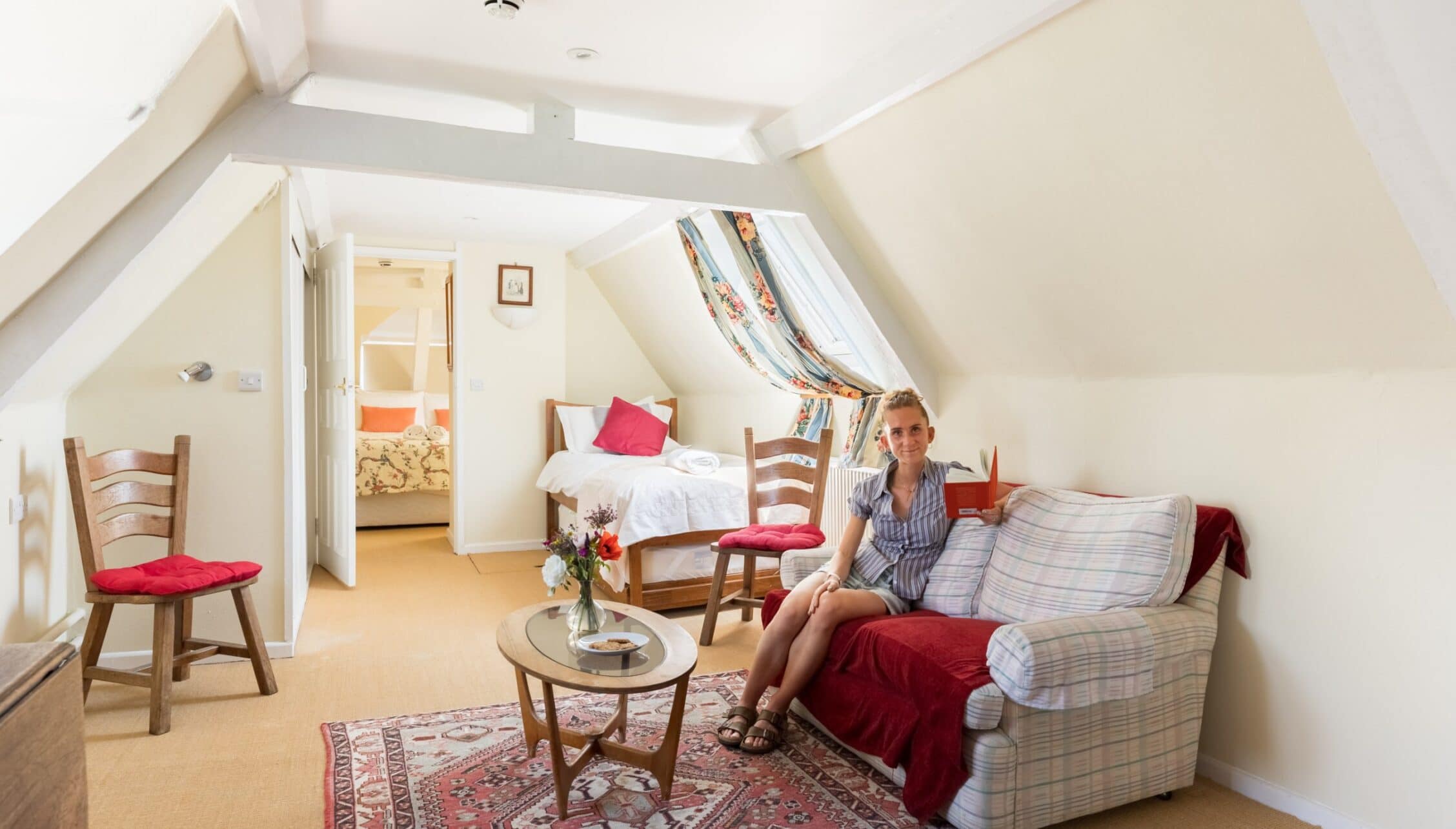 Upper Court, Gloucestershire – Bright attic room with sloped ceilings, sofa, and adjacent bedroom visible through doorway.