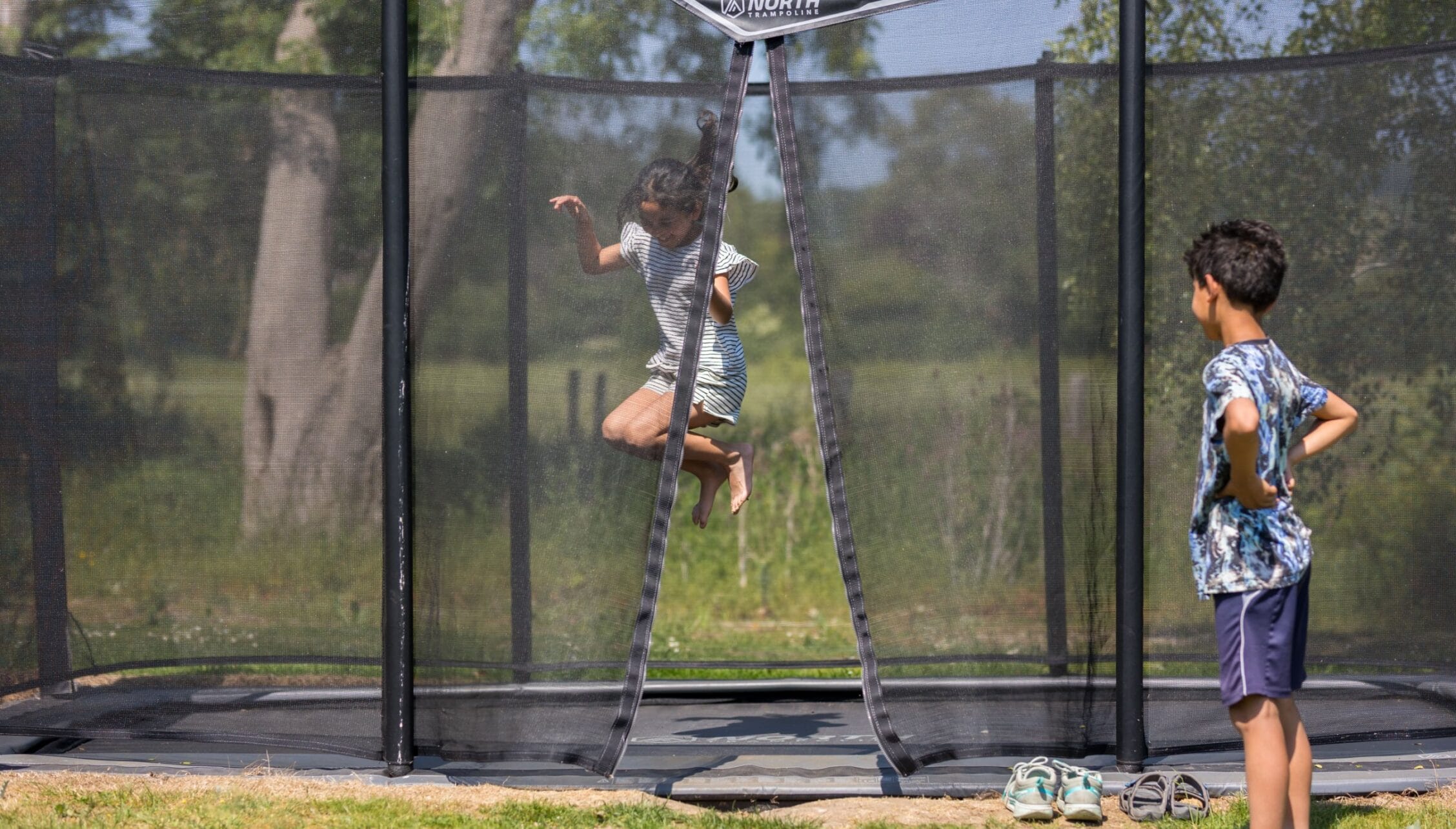 Upper Court, Gloucestershire – Children bouncing on a trampoline with safety enclosure in garden grounds.