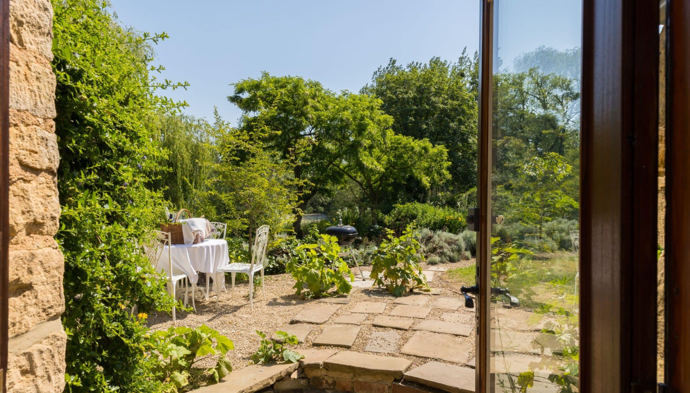 Upper Court, Gloucestershire – Stone terrace with table setting overlooking mature gardens and countryside.