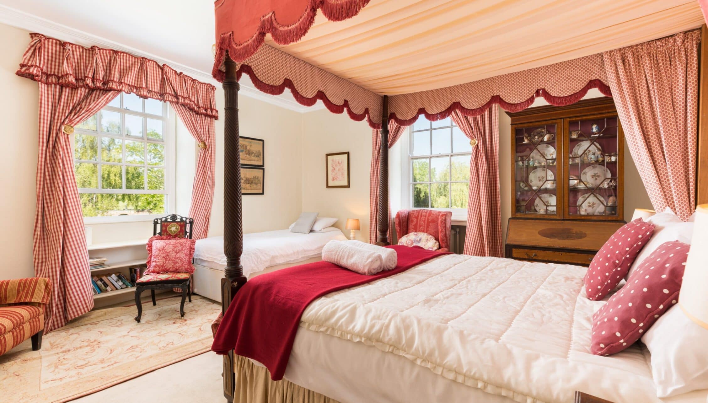 Upper Court, Gloucestershire – Four-poster bedroom with red fabric canopy and coordinating red striped curtains.