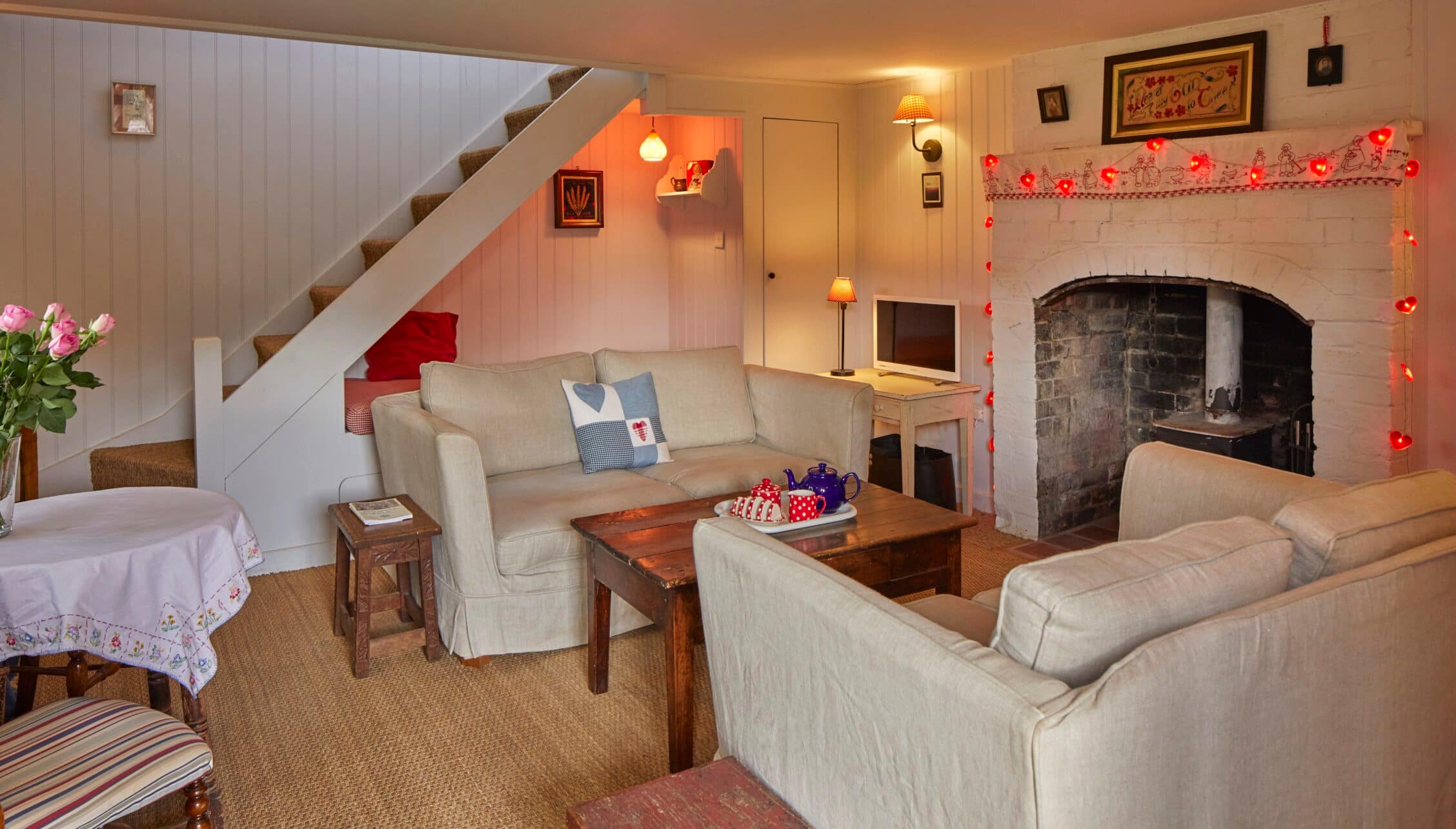 Barton Court, Herefordshire – Country lounge with cream sofas, stone fireplace and wooden staircase.