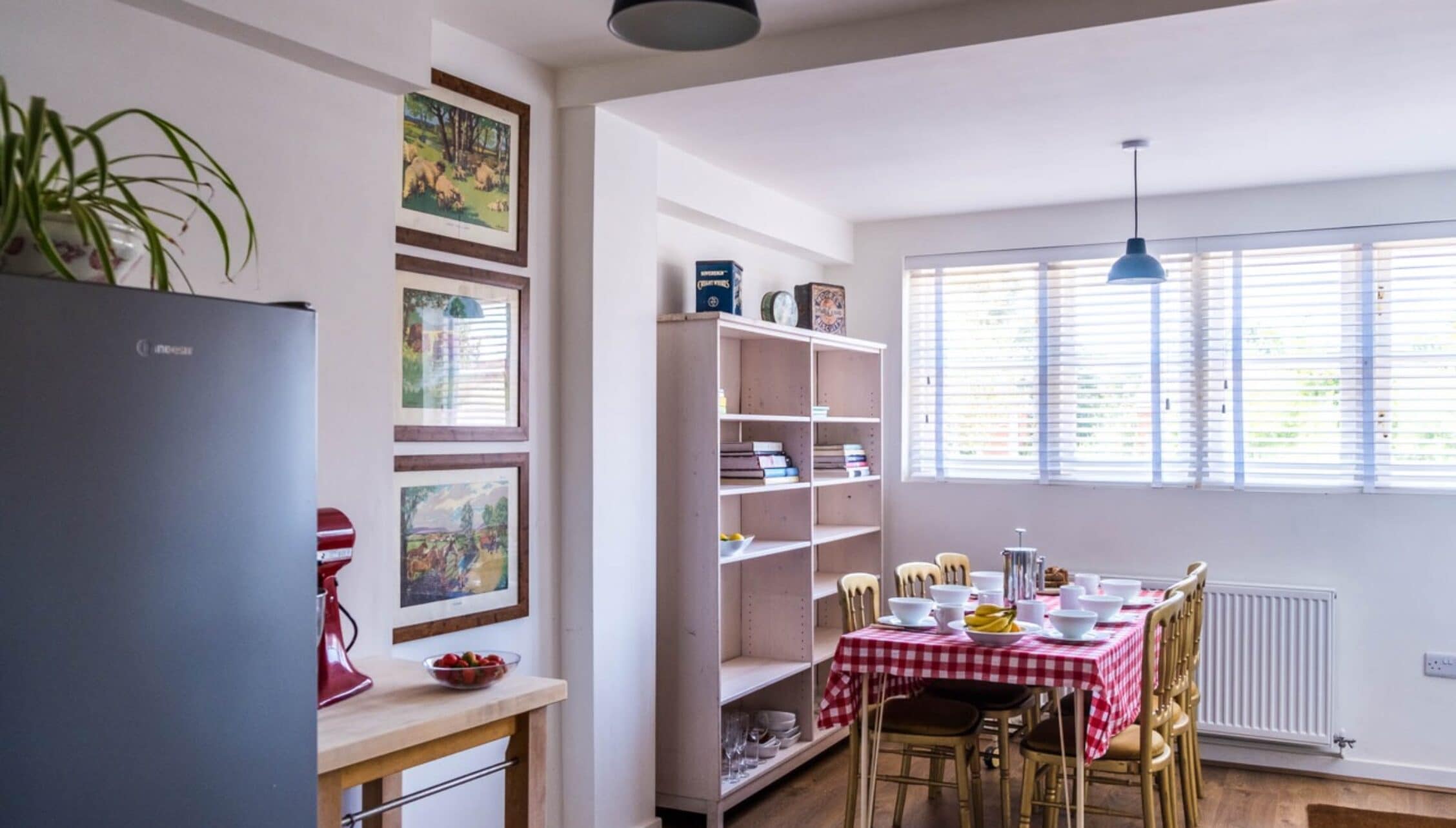 Barton Court, Herefordshire – Kitchen-dining area with red gingham tablecloth and open shelving units.