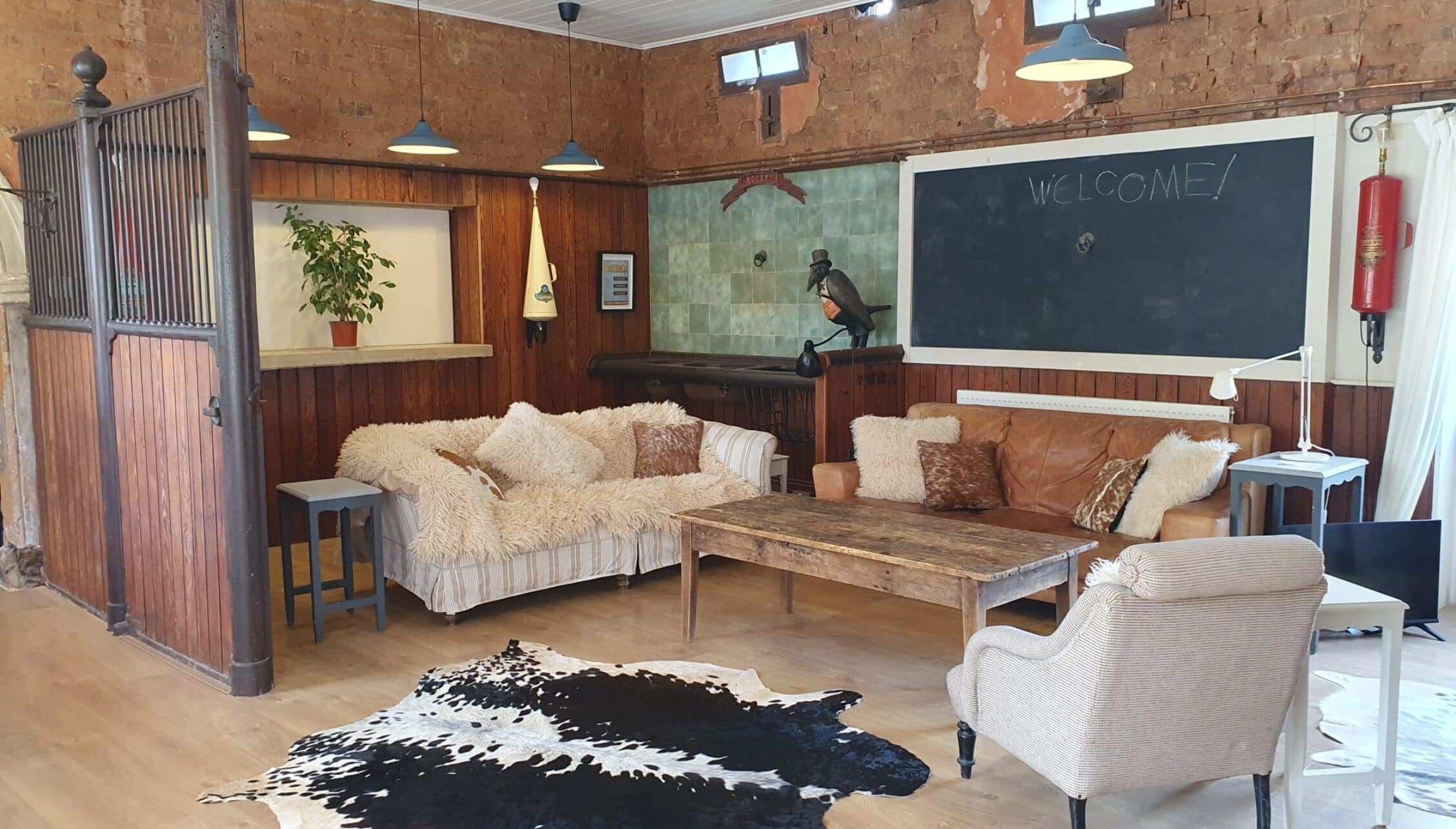 Barton Court, Herefordshire – Converted stable with wooden walls, sofas, and black and white cowhide rug.
