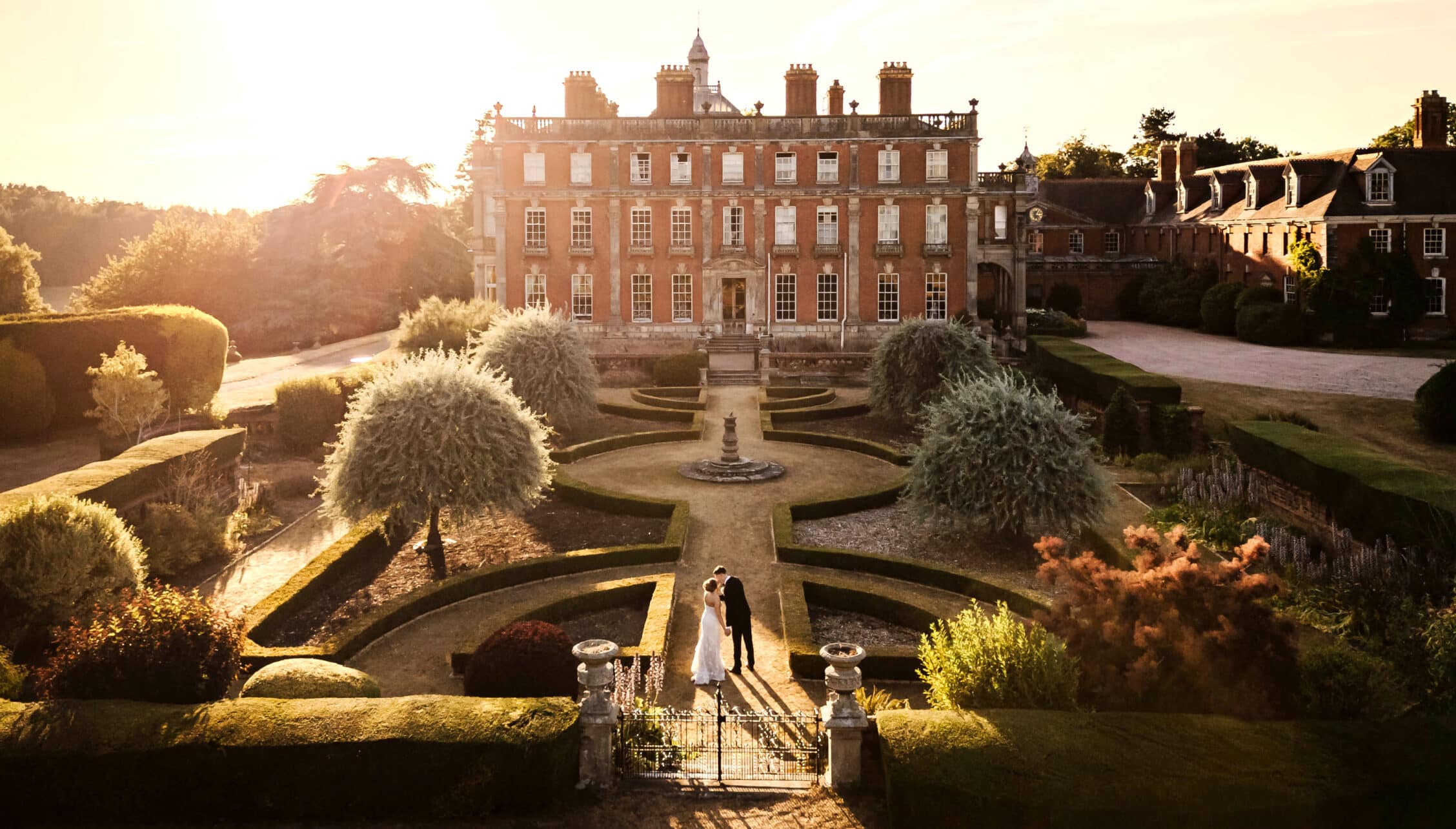 Berwick House, Shropshire – Red-brick country house with formal parterre garden and topiary at sunset.