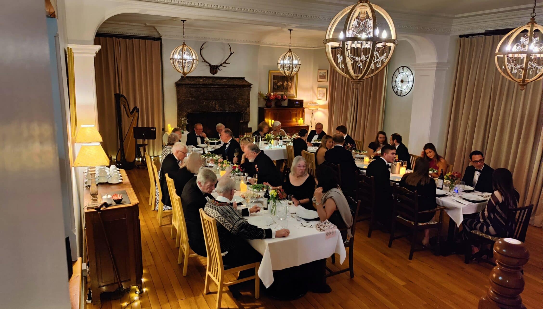 Bossington Hall, Somerset – Formal dining room with fireplace, crystal chandeliers, and seated guests at tables.