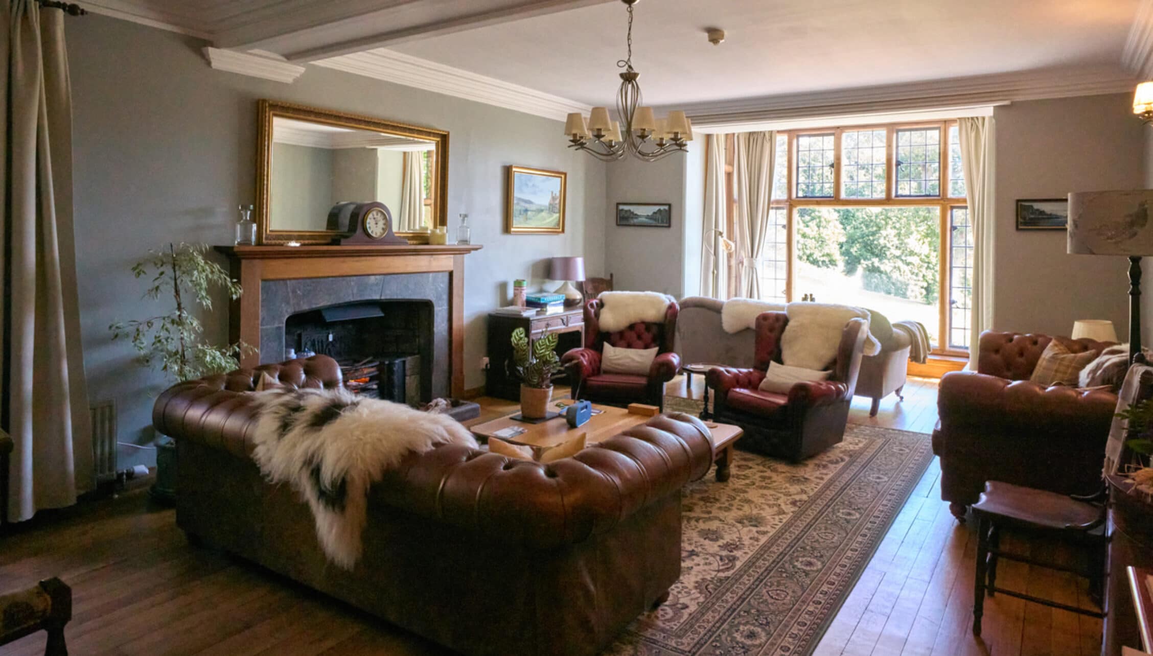 Bossington Hall, Somerset – Spacious drawing room with leather Chesterfield sofa, fireplace and French doors to grounds.