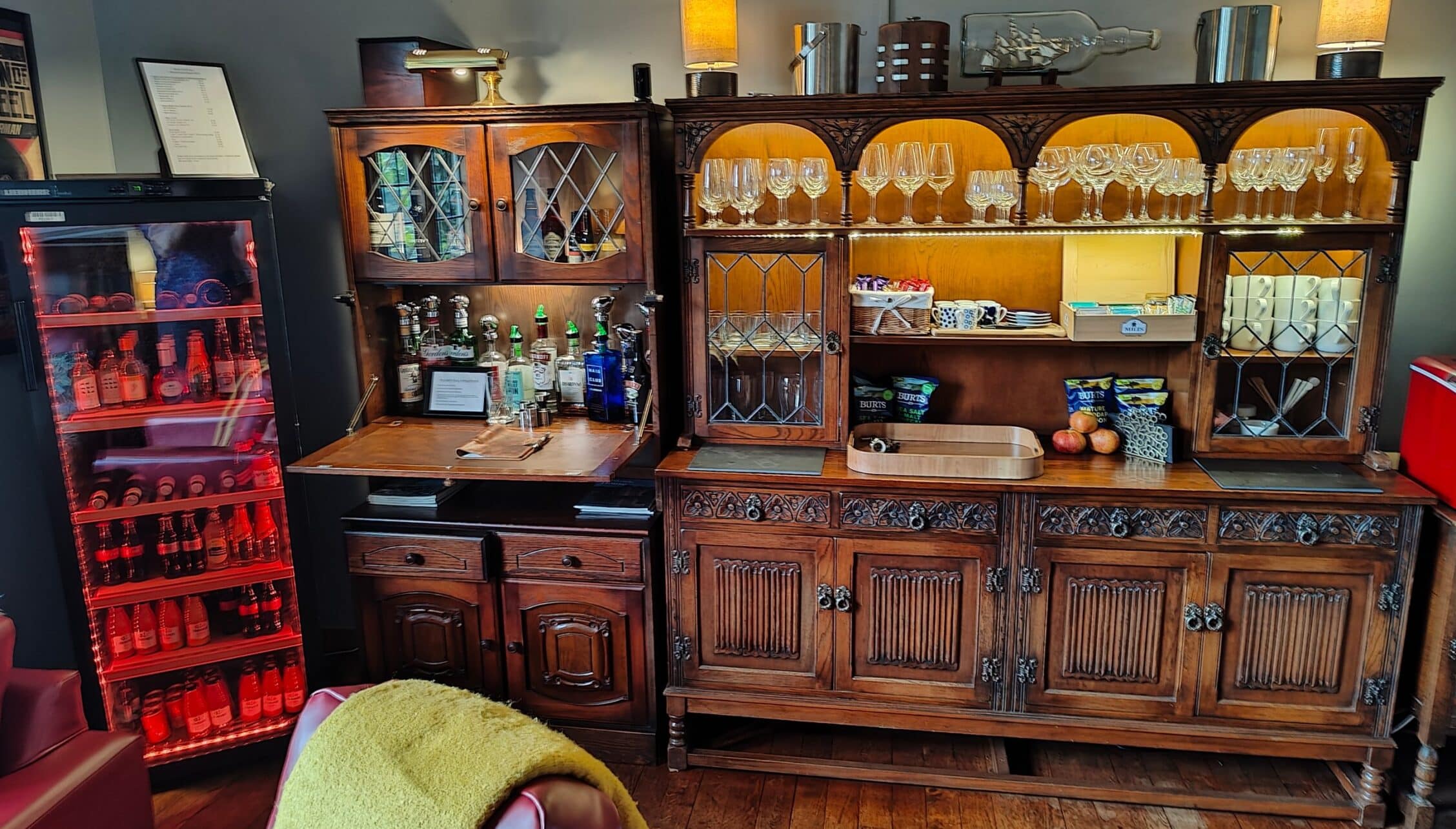 Bossington Hall, Somerset – Drinks cabinet with glazed doors, crystal glassware, and illuminated spirit bottles.