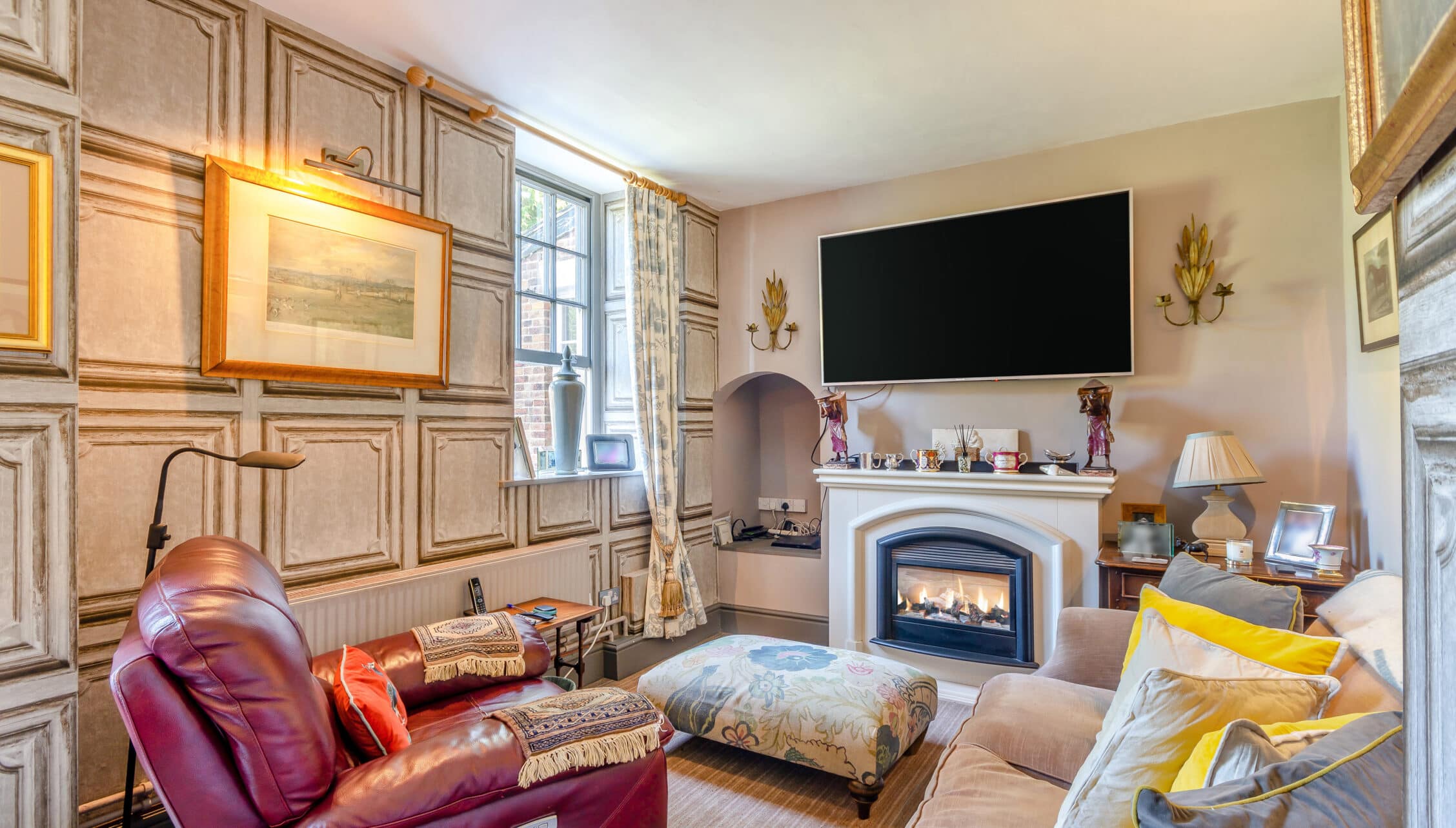 Breedon Hall, Leicestershire – Cream sitting room with burgundy leather armchair, gas fireplace, and wall-mounted television.