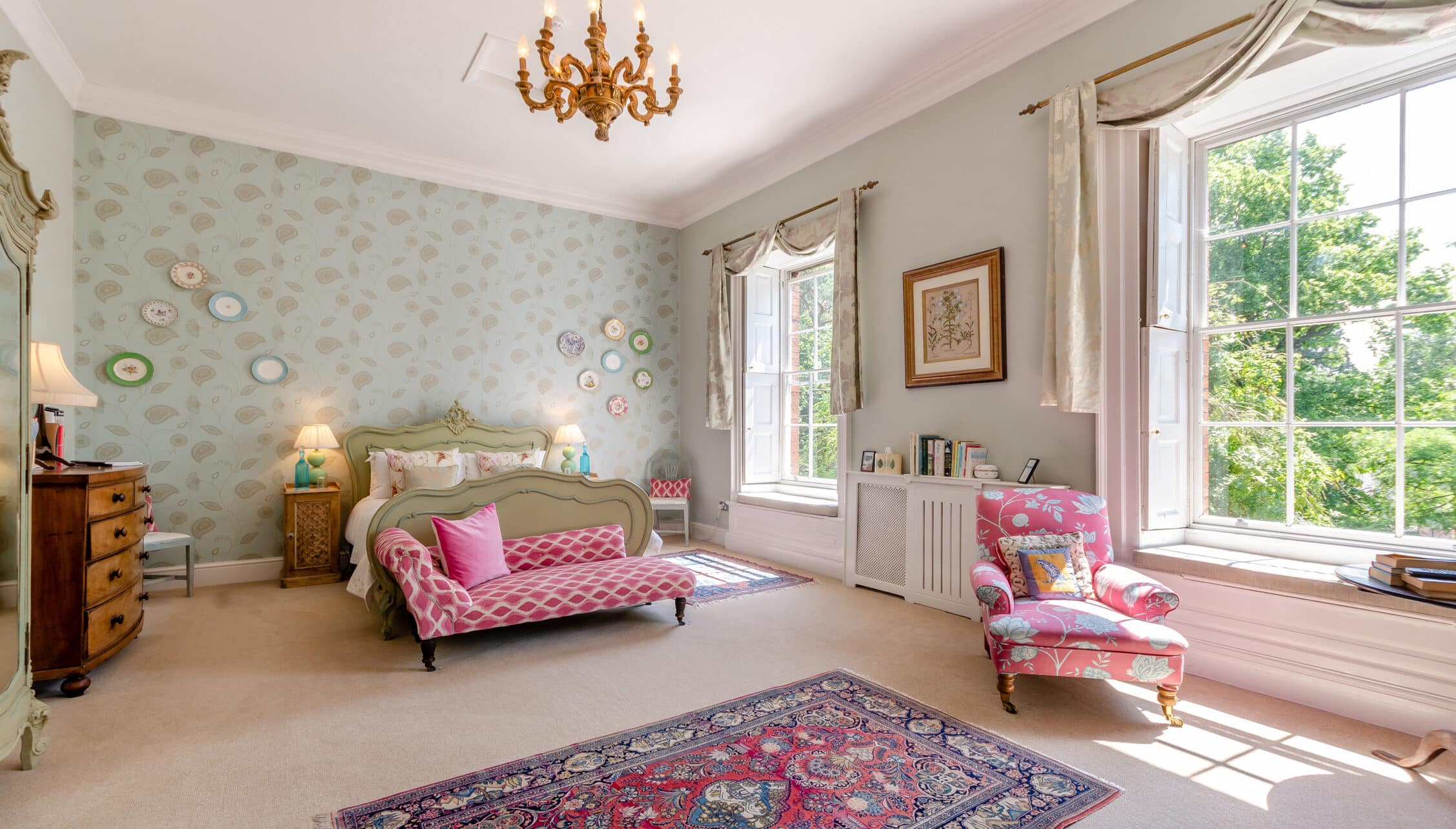 Breedon Hall, Leicestershire – Spacious bedroom with sash windows, decorative plate wall, and brass chandelier.