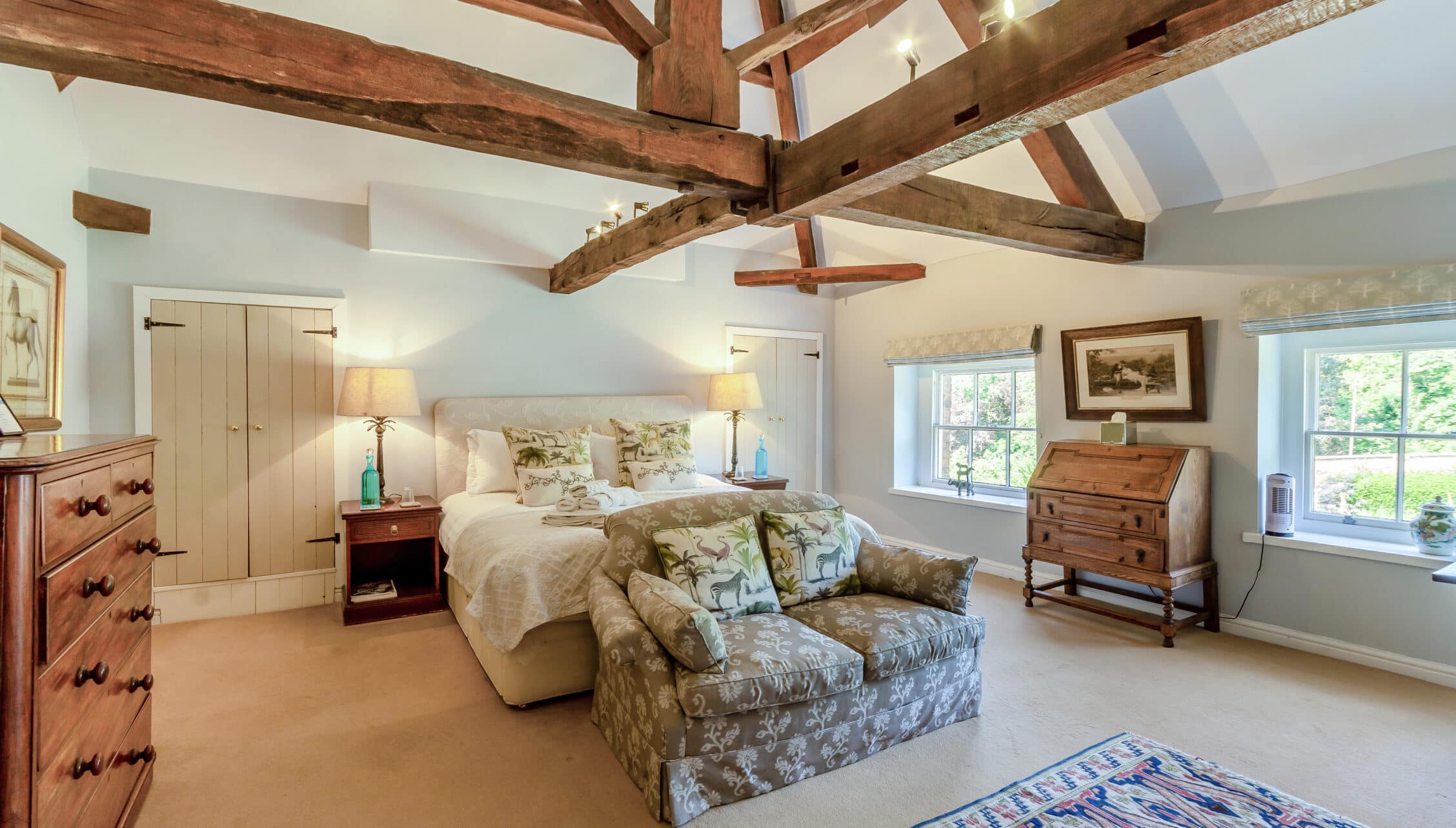 Breedon Hall, Leicestershire – Bedroom with exposed wooden beams, upholstered bed and patterned armchair.