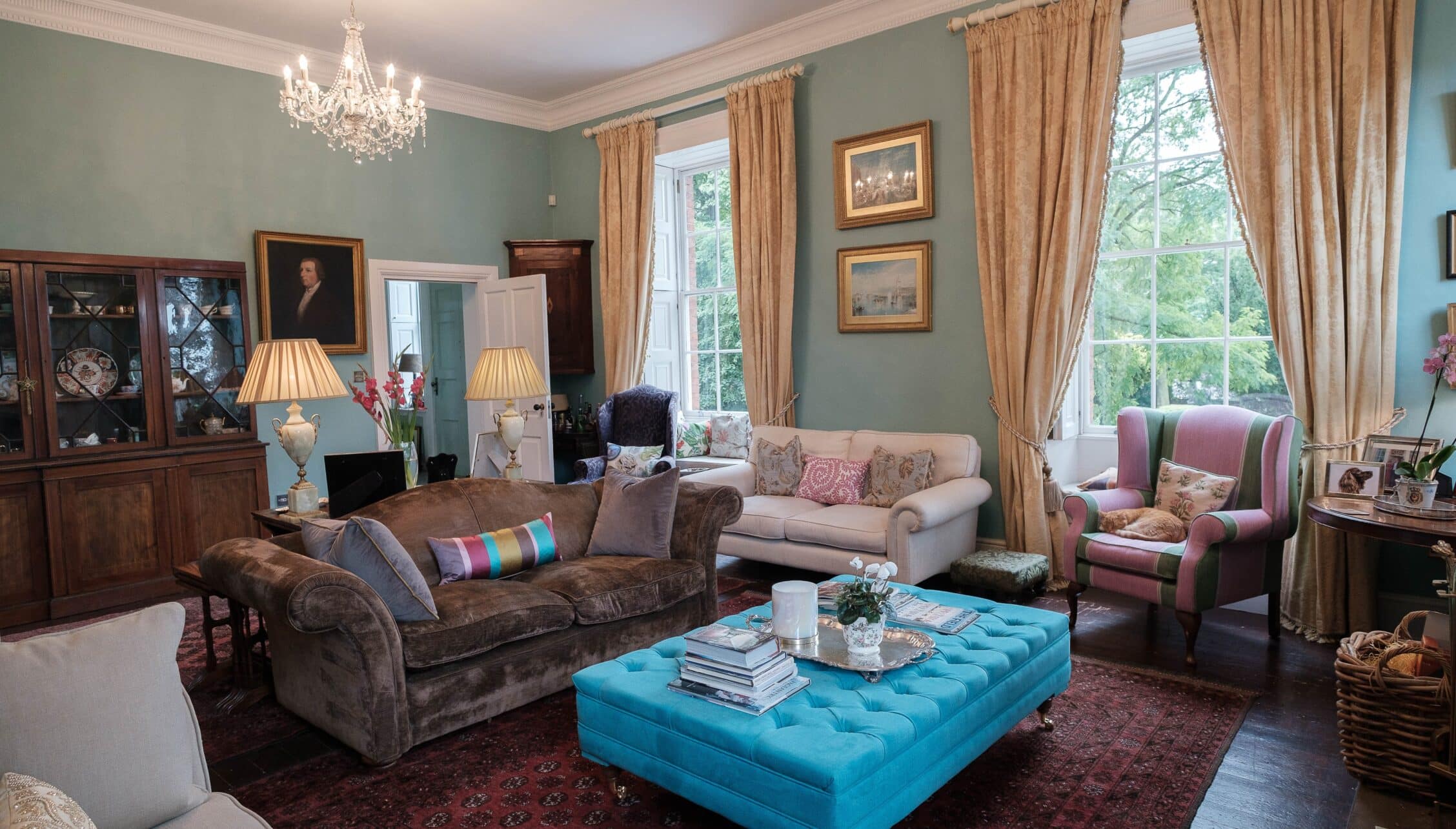Breedon Hall, Leicestershire – Sitting room with sage green walls, crystal chandelier, and turquoise buttoned ottoman.