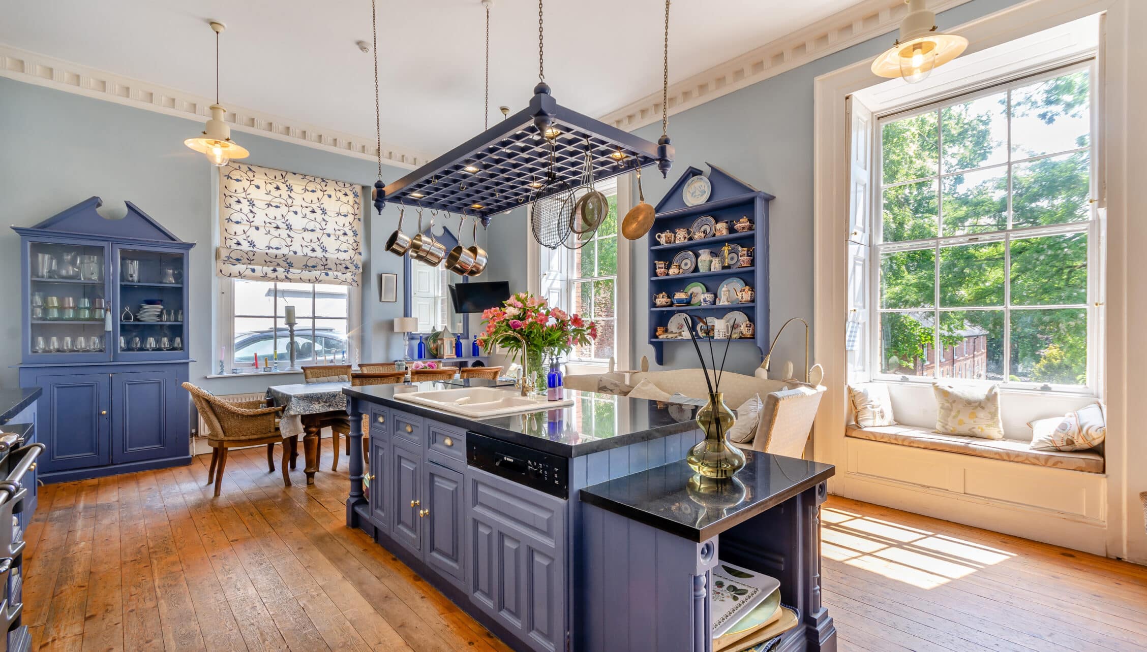 Breedon Hall, Leicestershire – Spacious kitchen with navy blue cabinetry, central island, and large window seat.